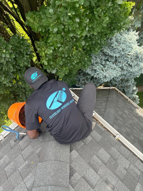 Silverlight technician performing manual eavestrough clearing and hand-bagging debris on a Toronto residential roof.