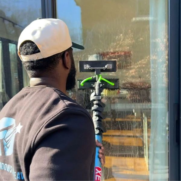 A Silverlight Windows and Eaves technician using a water-fed pole and brush to clean exterior residential glass doors in Mississauga, ON, demonstrating our streak-free pure water technology.