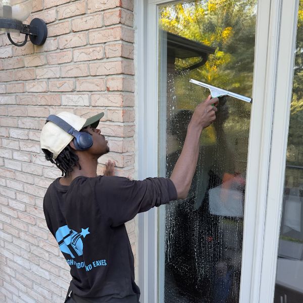 Professional technician performing hand-detailed window cleaning in Toronto using a squeegee for a streak-free finish.