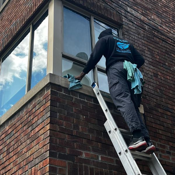 Stafan Lionel, founder of Silverlight, performing professional window cleaning on a 3rd-floor residential window using a ladder in Scarborough.