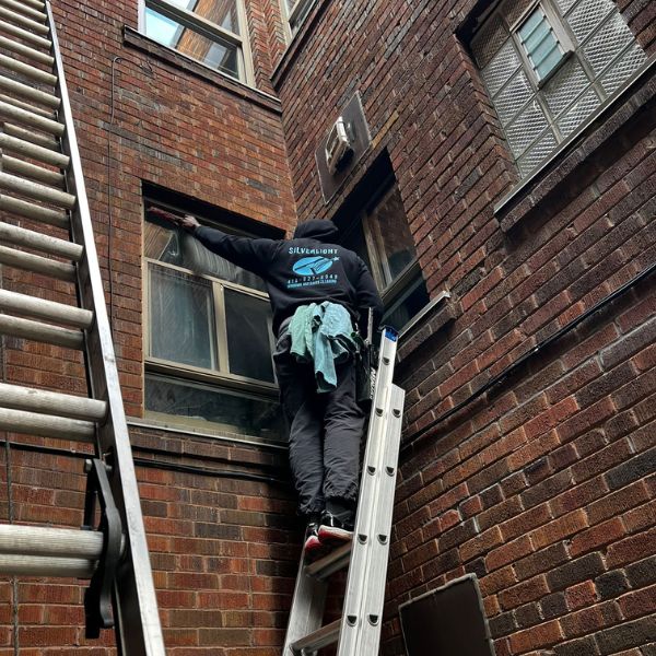 Stafan Lionel performing hand-detailed window cleaning on a historic brick home in Midtown Toronto.