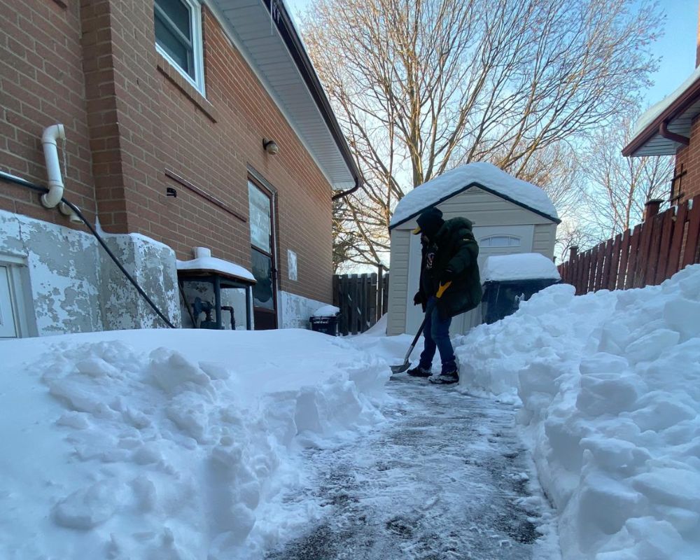 Stafan Lionel, owner of Silverlight Snow Removal, clearing a residential walkway during a heavy winter storm in Etobicoke.